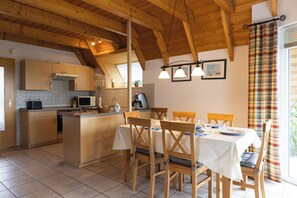 A kitchen with wooden cabinets, a microwave, and a dining area with a table and chairs.