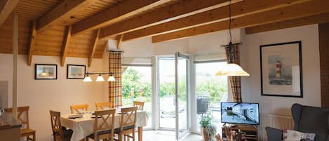 Een eetgedeelte met een houten tafel en stoelen, een televisie en een bank.
