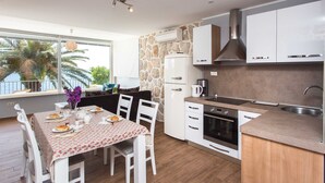 Una cocina moderna con armarios blancos, una pared de acento de piedra y un comedor con una mesa dispuesta para dos.