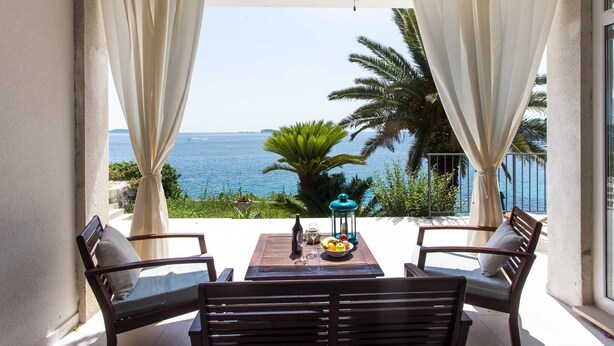 Un balcón con mesa, sillas y vista al mar.