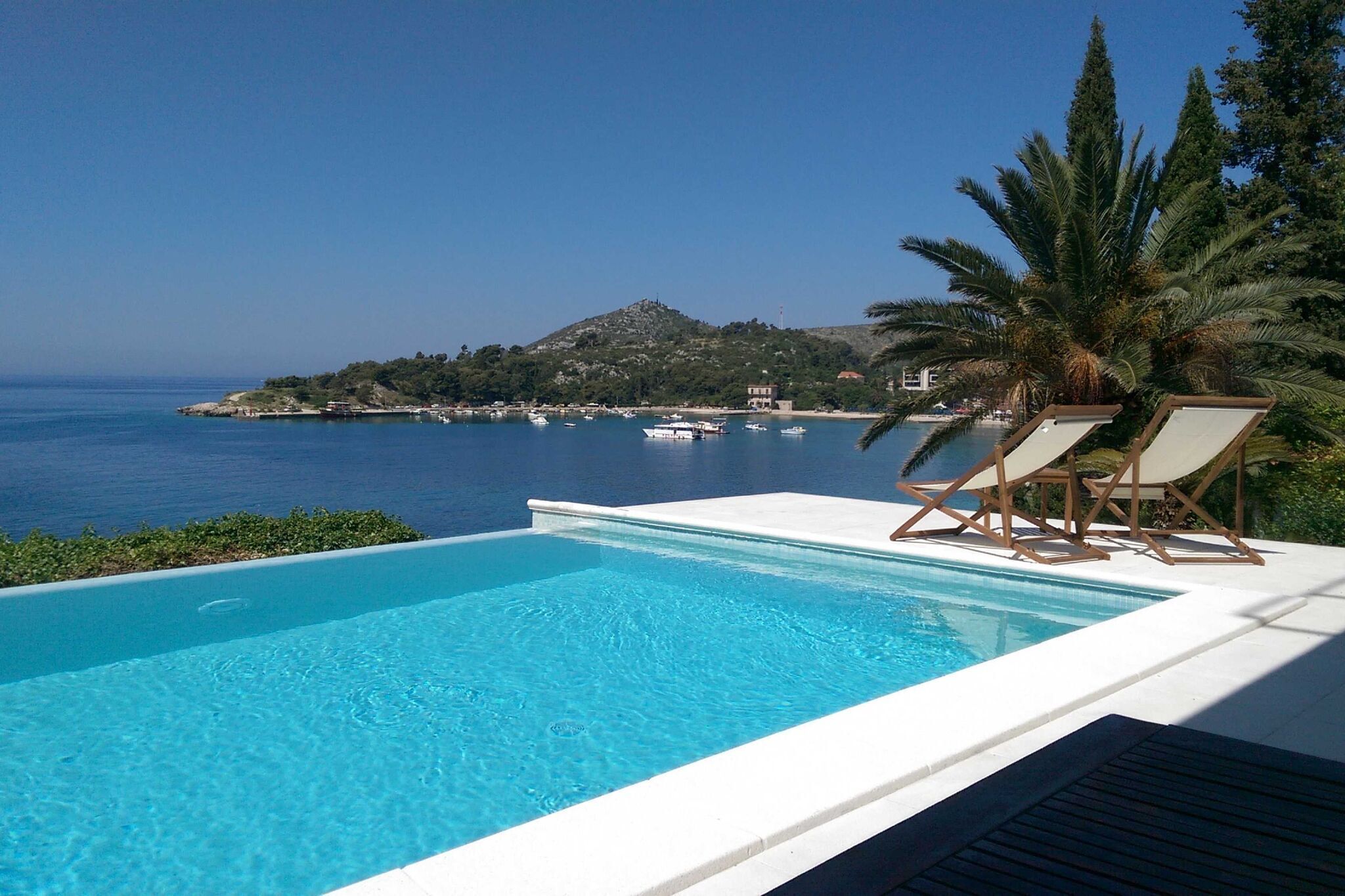 A swimming pool with a view of the sea and a hill.