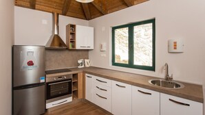 Eine moderne Küche mit Edelstahlgeräten, Holzbalken und einem Fenster mit Blick auf eine Steinmauer.