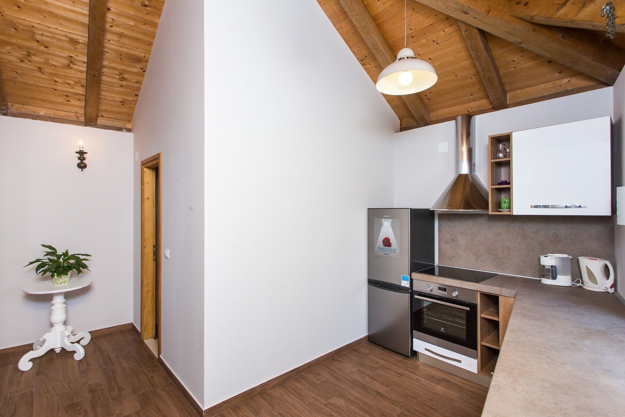 Eine kompakte Küche mit Backofen, Kühlschrank und einer Pendelleuchte.