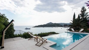 A pool with a view of the sea and a mountain in the distance.
