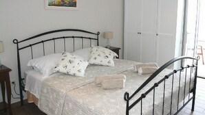 A bedroom with a bed, bedside tables, a wardrobe, and a painting on the wall.