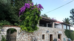 A stone building with a staircase leading to an entrance, a bicycle parked outside, and a sign indicating a cafe/bar.