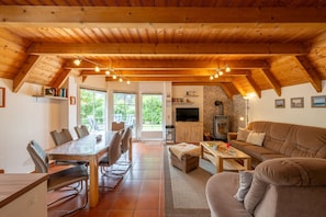 Un intérieur de chalet chaleureux avec un coin repas, un canapé et une cheminée.
