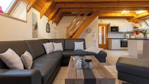A modern living room with a sectional sofa, a coffee table, and a kitchen in the background.