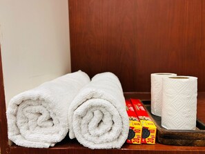 Two rolled white towels and three rolls of toilet paper on a wooden shelf. - Saroj Villa  (Agra)
