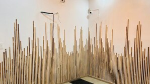 Quarto com parede de ripas de madeira, chão de piso preto e branco e luminária no teto.