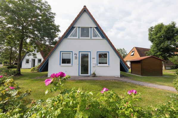 Ein zweistöckiges Haus mit einem Giebeldach, einer Haustür und einer kleinen Veranda.