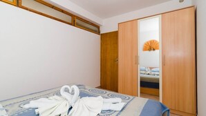 Een hotelkamer met een bed, een houten garderobe en een badkamer die door een open deur zichtbaar is.