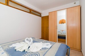 Een hotelkamer met een bed, een houten garderobe en een badkamer die door een open deur zichtbaar is.