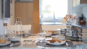 Une table de petit-déjeuner dressée avec des assiettes, des verres et un vase rempli de fleurs.