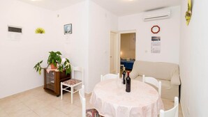A dining area with a round table, chairs, a potted plant, and a sofa.