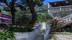 A stone staircase leading up to a building with a balcony, surrounded by greenery and a sign for 'La Dingue'.