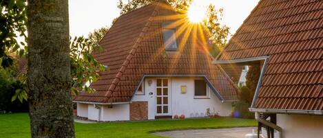Une maison traditionnelle avec un toit en pente, une porte d’entrée et une cheminée bien visible.