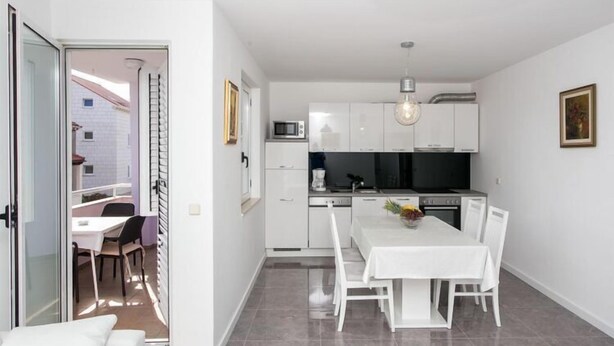 A modern kitchen with white cabinets, a dining table, and a pendant light.
