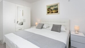 A bedroom with a large bed, a wardrobe, a bedside table with a lamp, and a framed picture on the wall.