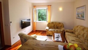 Un salon comprenant un canapé, un fauteuil et un téléviseur à écran plat fixé au mur.