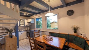 A kitchen with a dining area, wooden furniture, and a view of the outdoors. - Vacation home on the Wadden Sea. Harmonious and family-friendly. (Wurster Nordseeküste)