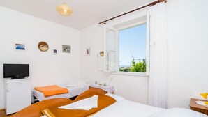 Hotellihuone, jossa on kaksi sänkyä, televisio, pieni pöytä ja ikkuna, josta on näkymä.