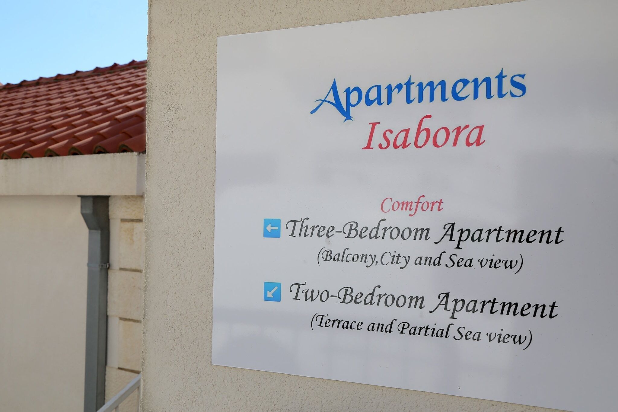 Señal que enumera apartamentos en Isabora, con opciones de apartamentos de tres y dos dormitorios, e incluye vistas.