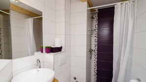 A modern bathroom with a white sink, a shower with a dark tiled wall, and a white curtain. - Lavender Garden Apartments - Studio Apartment (Ground floor) - APT 1 (Dubrovnik)