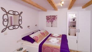 A bedroom with a bed, a wardrobe, a mirror, and a painting. - Lavender Garden Apartments - Studio Apartment (Ground floor) - APT 1 (Dubrovnik)