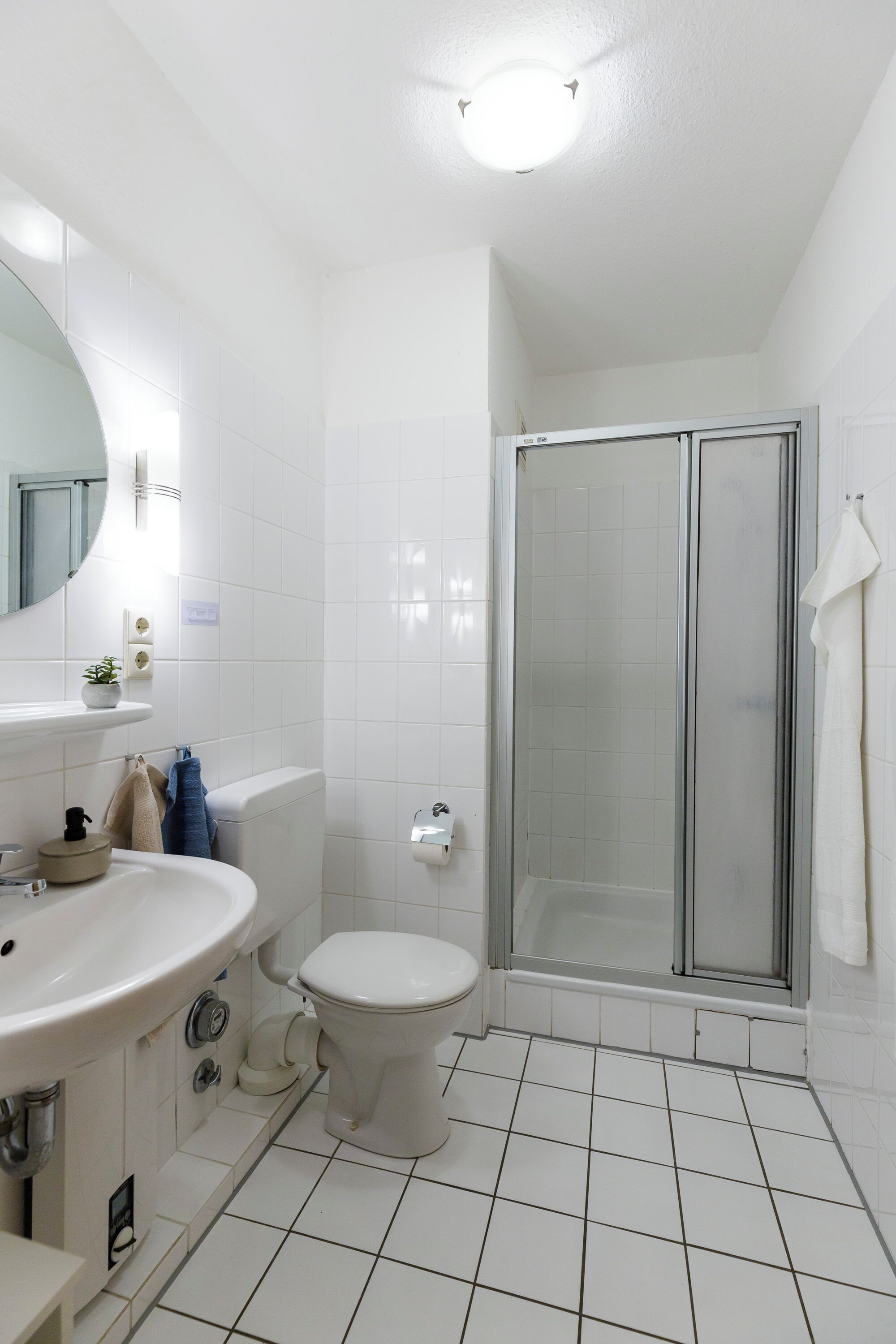 A bathroom with a white sink, toilet, and glass-enclosed shower.