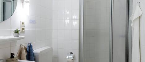 A bathroom with a white sink, toilet, and glass-enclosed shower.