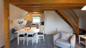 A cozy interior with a dining area, a sofa, and a staircase.