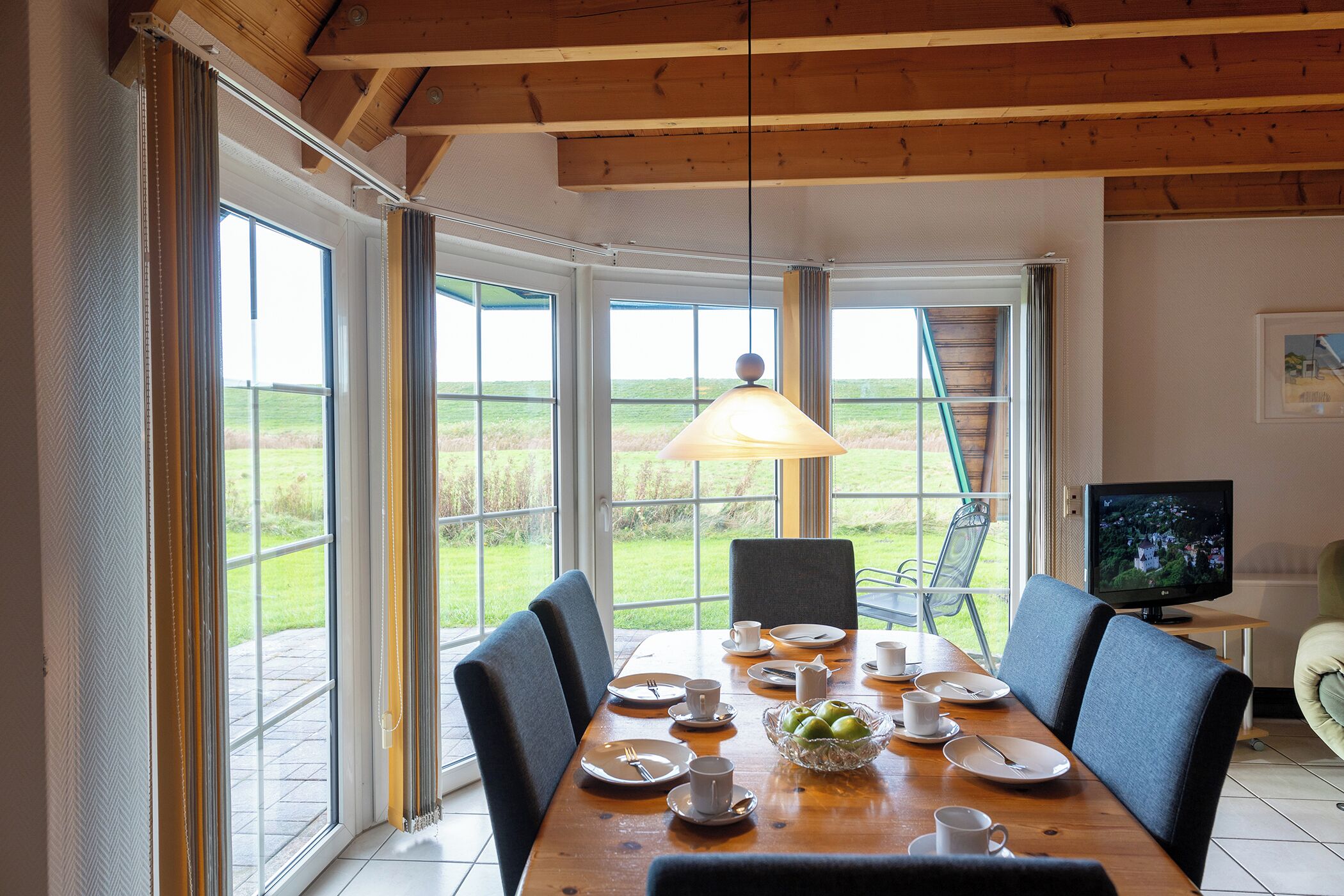 A dining area with a wooden table, chairs, and a television.
