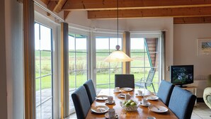 A dining area with a wooden table, chairs, and a television.
