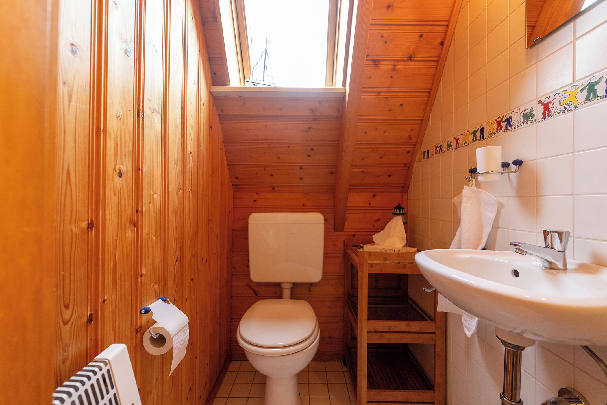 Un baño con paneles de madera, un inodoro, un lavamanos y una ventana.