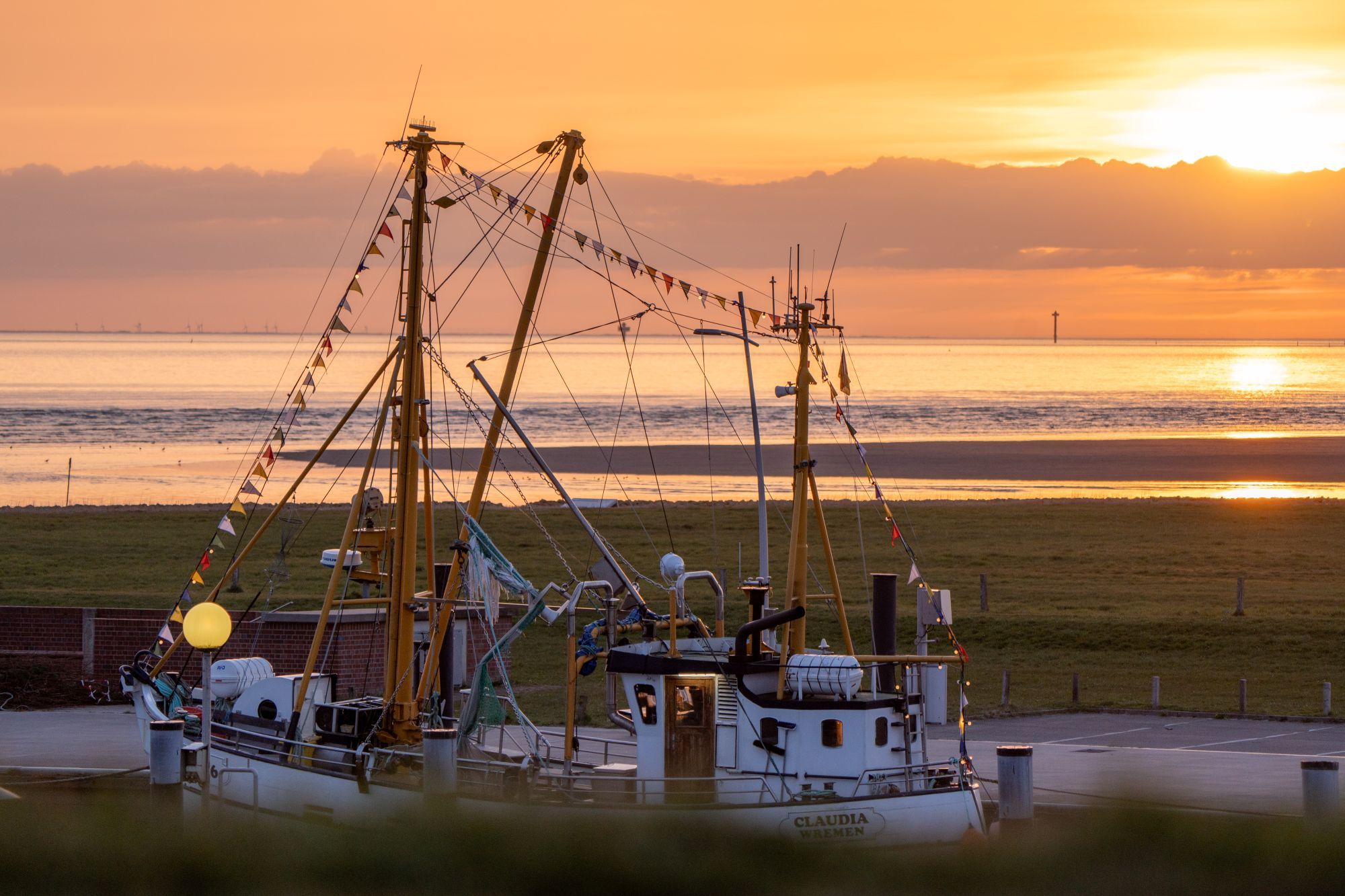 A fishing boat docked at a pier with a sunset in the background.