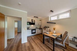 Una cocina moderna con zona de comedor, suelo de madera y ventana con persianas.