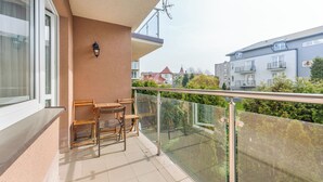 A balcony with a glass railing, a wooden table, and two chairs. - Apartament Sun & Snow Siedleckiego 8 (Wladyslawowo)