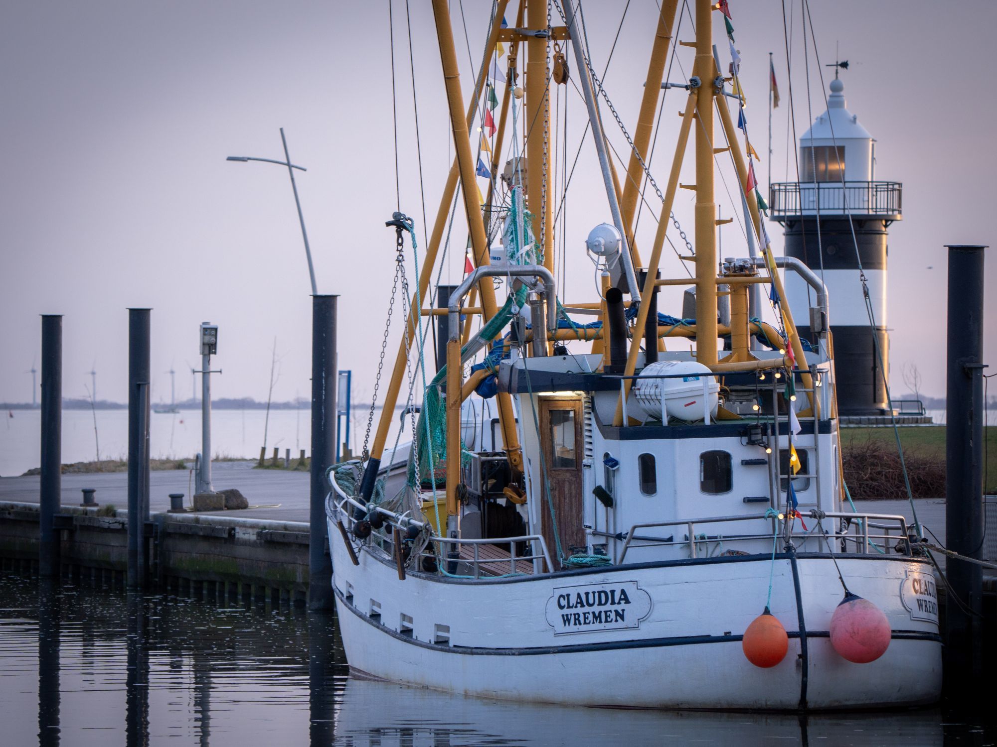 Un bateau blanc, baptisé CLAUDIA WREMEN, était amarré à un quai, avec un phare en arrière-plan.