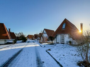 A residential street with snow-covered ground and houses with pitched roofs.