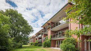 A multi-story brick building with balconies and a well-maintained lawn.