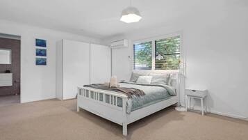 A bedroom with a bed, a bedside table, a wardrobe, and a window with blinds.