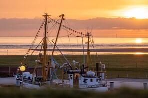 A fishing boat docked at a pier with a sunset in the background.