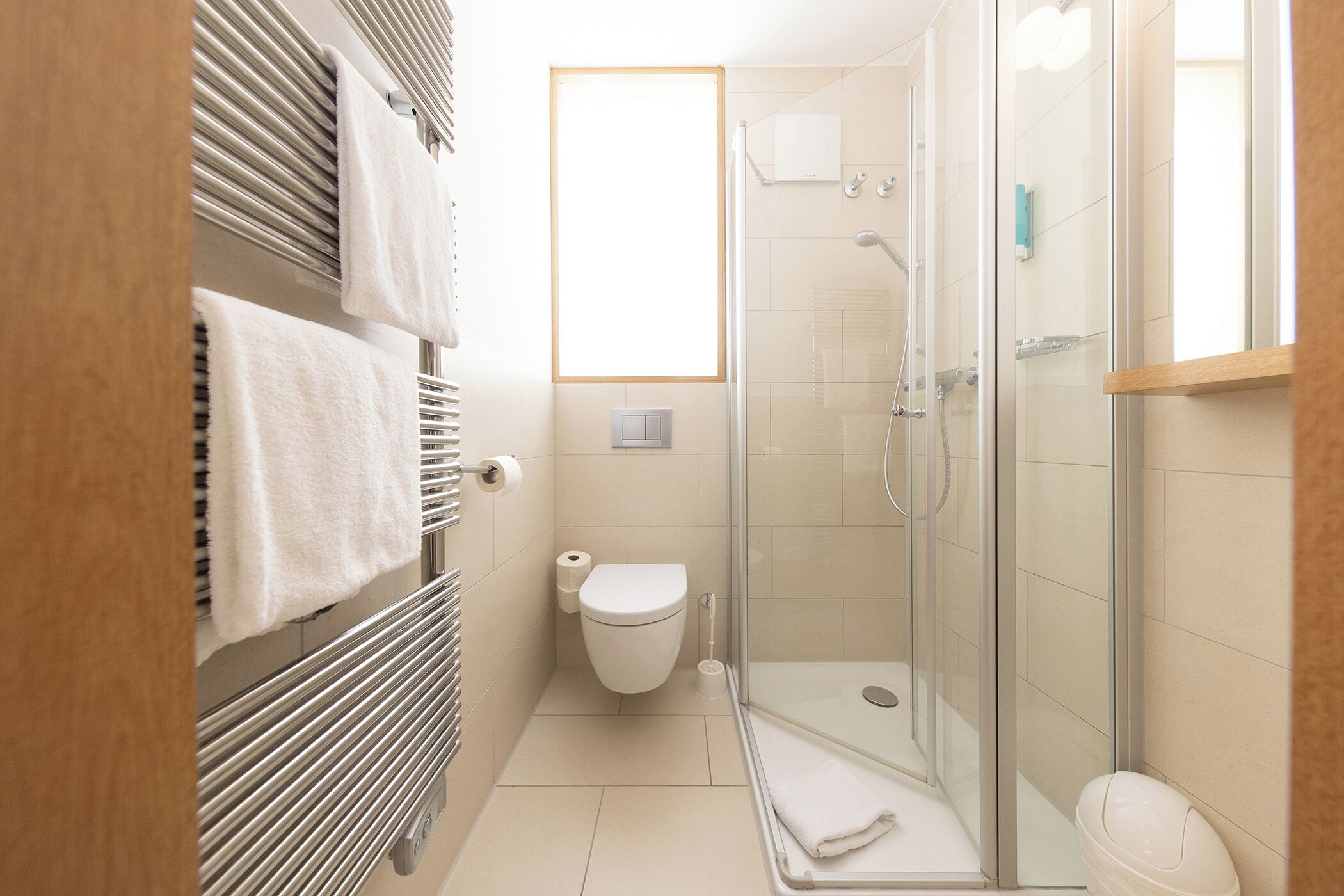 Ein modernes Badezimmer mit Duschkabine aus Glas, Toilette und Handtuchhalter.