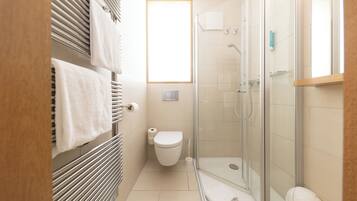 Ein modernes Badezimmer mit Duschkabine aus Glas, Toilette und Handtuchhalter.