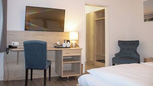 Ein Hotelzimmer mit Bett, Schreibtisch mit Stuhl, Fernseher, Lampe und Kleiderschrank.