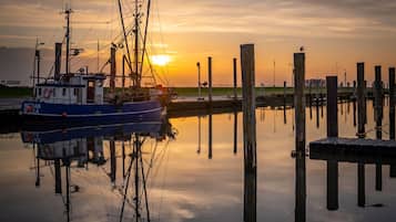 Een boot aangemeerd aan een steiger, met een zonsondergang op de achtergrond.