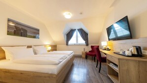 A hotel room with a bed, a desk with a chair, a TV, and a painting on the wall. - Double room 115. Cozy and dog-friendly. (Wurster Nordseeküste)