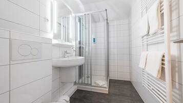 Ein modernes Badezimmer mit Duschkabine aus Glas, einem weißen Waschbecken und einem Handtuchhalter.