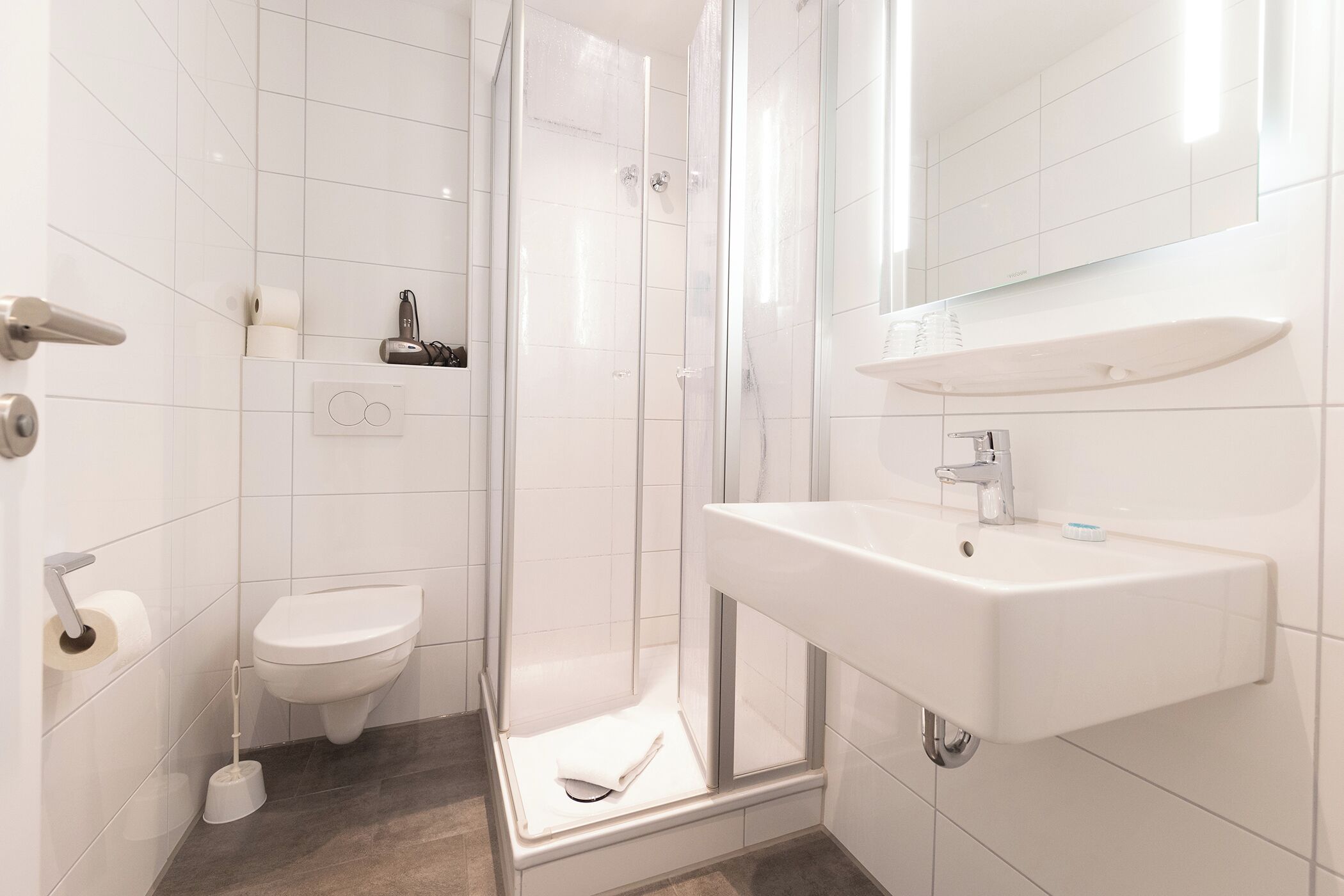 Une salle de bain moderne équipée de toilettes, d’une douche et d’un lavabo.